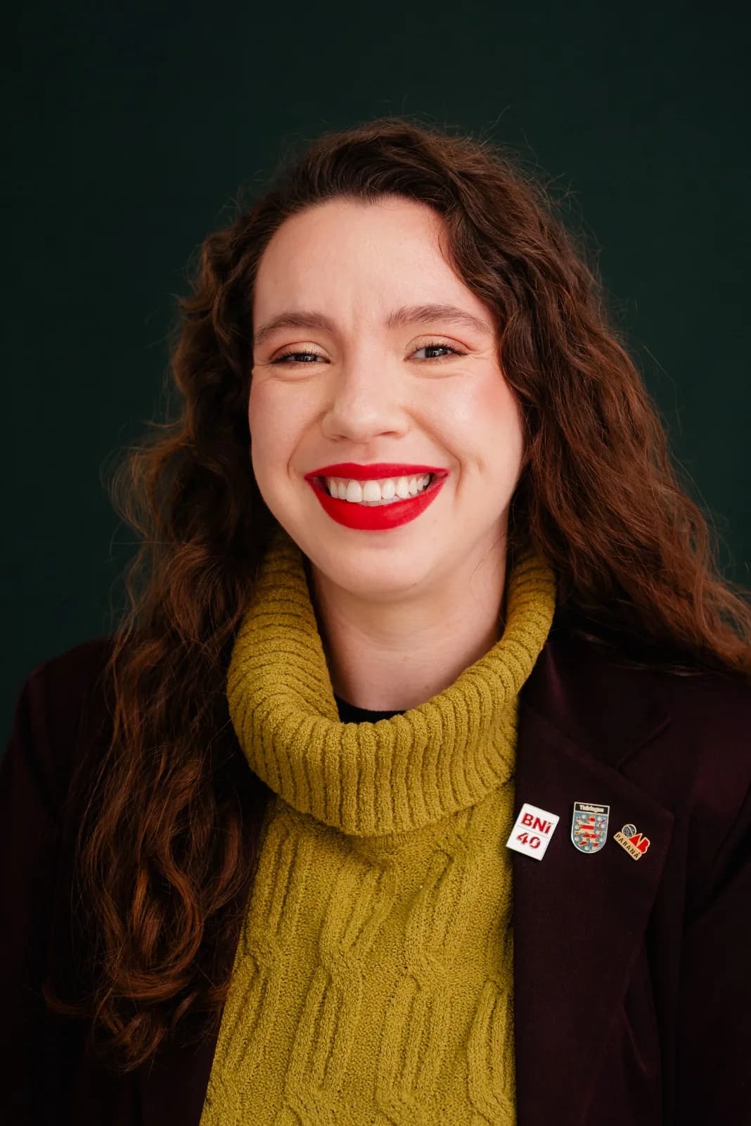 Ellen Landgraf, advogada especializada em registro de marca, sorrindo, de blazer bordô e gola alta mostarda.